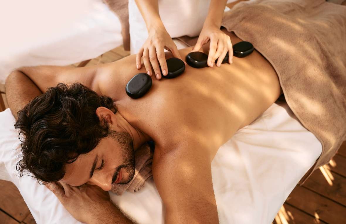 A man receiving a hot stone massage, with smooth, heated stones placed on his back.