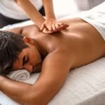 A man receiving a full back massage with lotion or oil for smooth, gliding strokes.