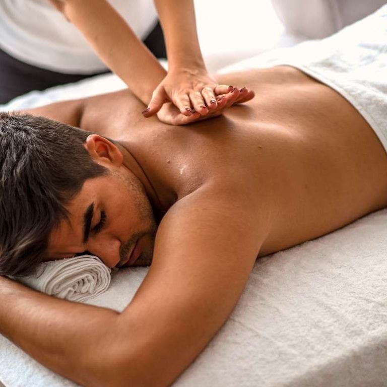 A man receiving a full back massage with lotion or oil for smooth, gliding strokes.